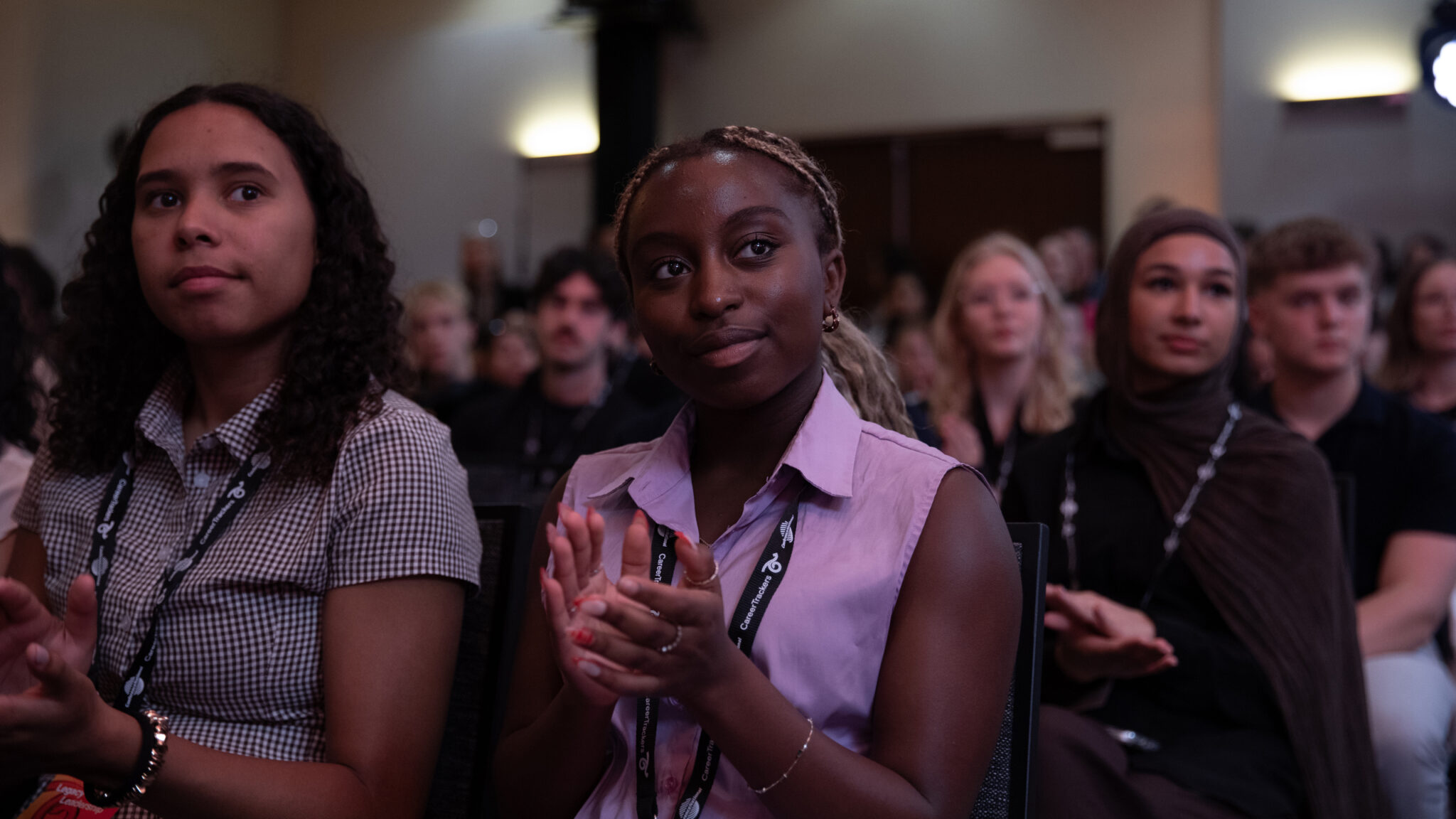 CareerTrackers interns applauding at a program event, wearing CareerTrackers lanyards.