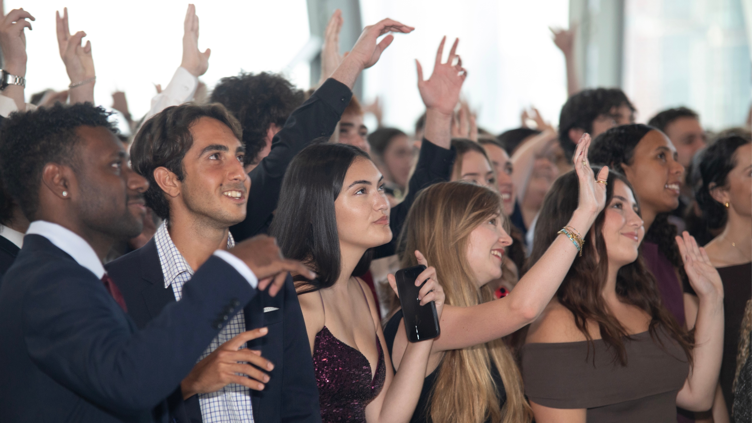 A crowd of CareerTrackers students cheering and applauding at a celebration event.