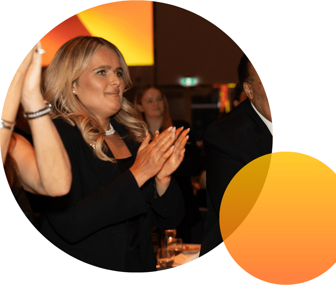 A CareerTrackers alumna applauding at a gala celebration, framed in a circle with a gold-to-orange gradient accent.