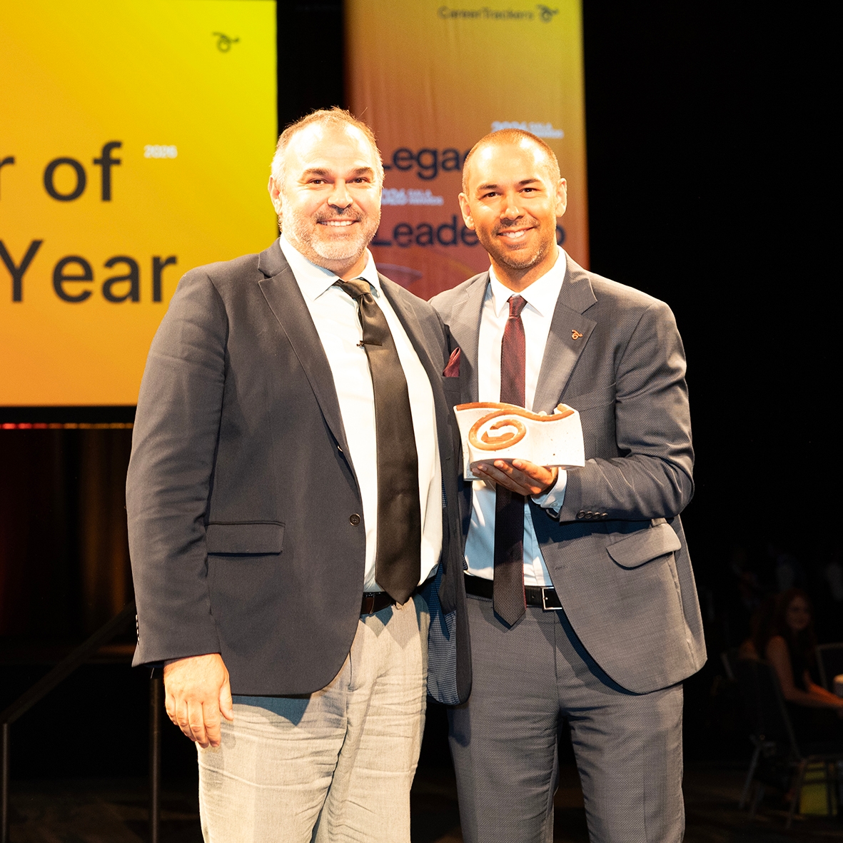 CareerTrackers Gala Awards presenters celebrating on stage with an award.