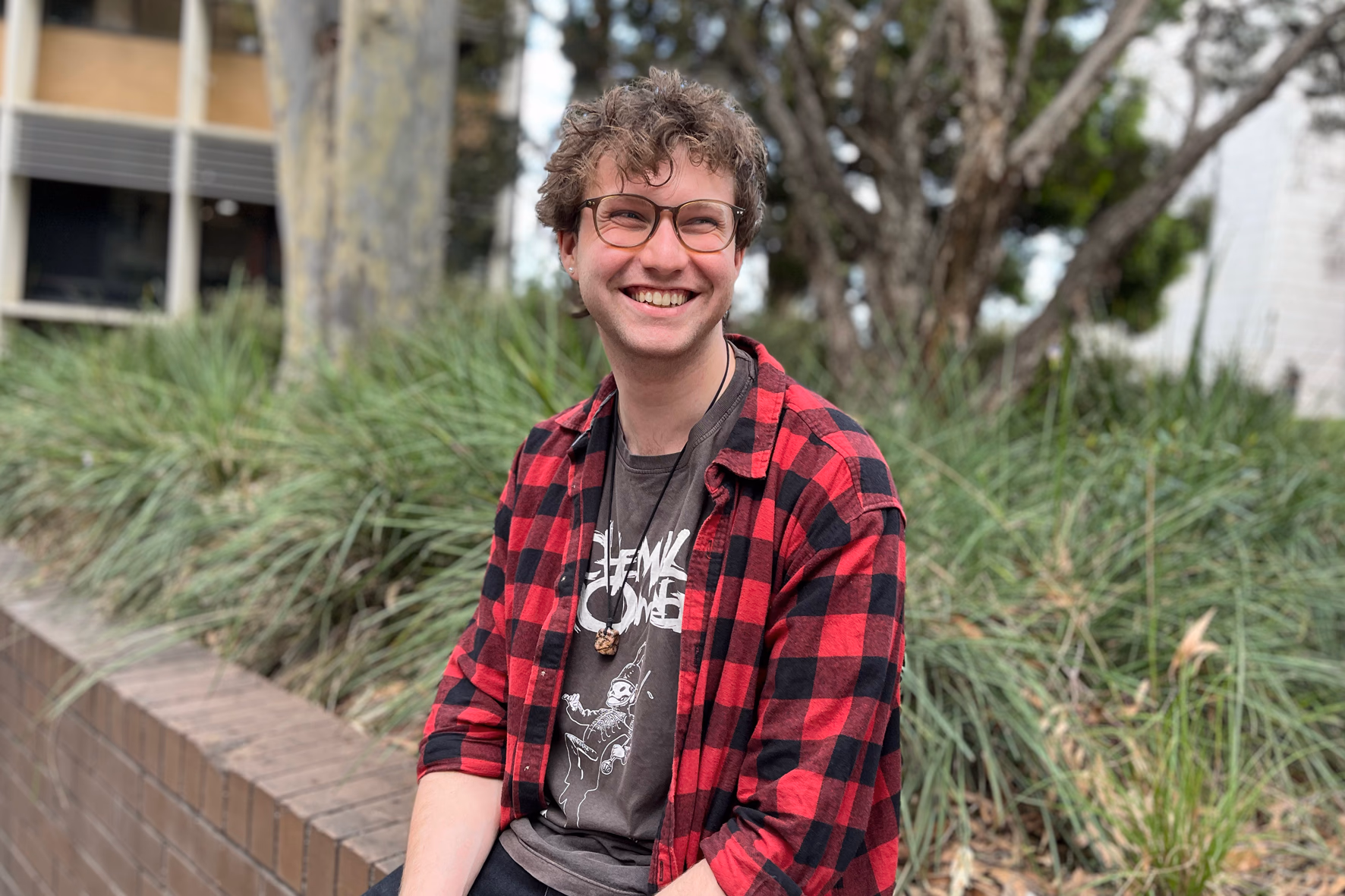 John Sopar seated outside on campus